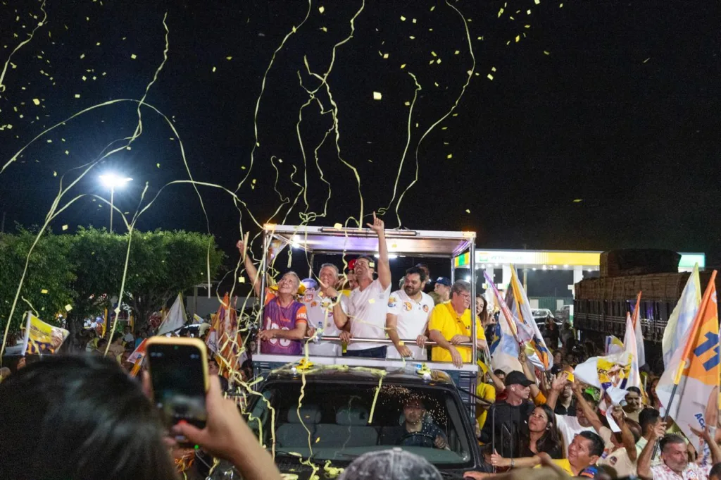 Carro aberto com Lucas Ribeiro e aliados recebe chuva de fitas e serpentinas amarelas no meio da comemoração popular.